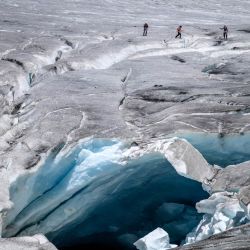 Esta fotografía muestra a un grupo de excursionistas abriéndose paso junto a un agujero de deshielo en el glaciar del Ródano, sobre Gletsch, en los Alpes suizos. Tras el calor extremo de junio y julio, el glaciar del Ródano, en Suiza, ha perdido más de cuatro metros de hielo en un solo mes, según el glaciólogo Matthias Huss, director de la Red Suiza de Monitoreo de Glaciares (GLAMOS), citado por la agencia de noticias suiza Keystone-SDA. El retroceso del glaciar, con un promedio de unos 10 centímetros diarios, ha generado preocupación ante la posibilidad de que 2026 pueda igualar la pérdida récord de hielo registrada en 2022. | Foto:FABRICE COFFRINI / AFP