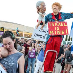 Un manifestante disfrazado del presidente estadounidense Donald Trump, sosteniendo una marioneta que representa al primer ministro israelí Benjamin Netanyahu, posa mientras una mujer sostiene a un bebé en brazos durante una manifestación en Tel Aviv, en protesta contra los recientes ataques violentos de colonos israelíes en Cisjordania, territorio ocupado por Israel. La violencia en Cisjordania se ha intensificado desde el inicio de la guerra de Gaza con el ataque de Hamás contra Israel el 7 de octubre de 2023, y grupos de derechos humanos y la ONU informan de ataques casi diarios por parte de colonos israelíes. | Foto:JACK GUEZ / AFP