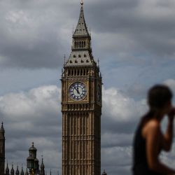 Una mujer se sienta en la orilla sur del río Támesis con vistas a la Torre Elizabeth (al fondo, en el centro), conocida popularmente como "Big Ben", y al Palacio de Westminster (abajo, a la izquierda), en la orilla norte, en Westminster, en el centro de Londres. | Foto:HENRY NICHOLLS / AFP