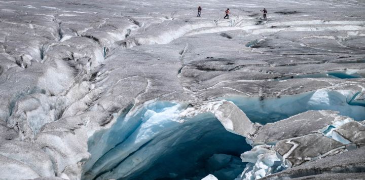 Esta fotografía muestra a un grupo de excursionistas abriéndose paso junto a un agujero de deshielo en el glaciar del Ródano, sobre Gletsch, en los Alpes suizos. Tras el calor extremo de junio y julio, el glaciar del Ródano, en Suiza, ha perdido más de cuatro metros de hielo en un solo mes, según el glaciólogo Matthias Huss, director de la Red Suiza de Monitoreo de Glaciares (GLAMOS), citado por la agencia de noticias suiza Keystone-SDA. El retroceso del glaciar, con un promedio de unos 10 centímetros diarios, ha generado preocupación ante la posibilidad de que 2026 pueda igualar la pérdida récord de hielo registrada en 2022.