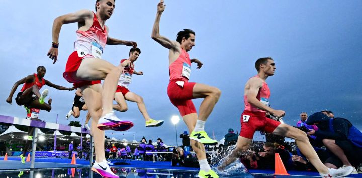 Kristian Imroth (izq.) de Inglaterra y Jean-Simon Desgagnes (centro) de Canadá compiten en la final de los 3000 metros con obstáculos masculinos durante la prueba de atletismo en el estadio Scotstoun de Glasgow, en el cuarto día de los Juegos de la Commonwealth en Glasgow, Escocia.