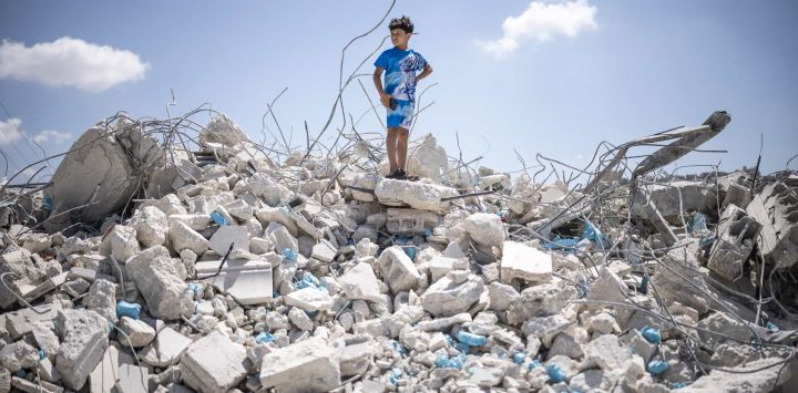 Un niño palestino se encuentra sobre un montón de escombros de un edificio que albergaba tiendas y apartamentos, demolido por las fuerzas israelíes alegando falta de permiso de construcción, en Arraba, al sur de la ciudad palestina de Jenin, en el norte de Cisjordania, territorio ocupado por Israel.