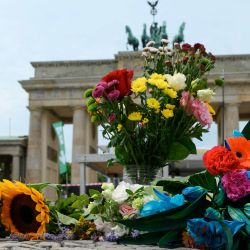 Varias personas colocaron ramos de flores frente a la emblemática Puerta de Brandeburgo, antes de un acto de duelo comunitario, un día después del atropello perpetrado en las inmediaciones del desfile del Día de Christopher Street (CSD) de Berlín, que dejó un muerto y 16 heridos en el parque Tiergarten. | Foto:RALF HIRSCHBERGER / AFP