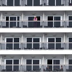 Un pasajero de crucero observa desde el balcón de un camarote a bordo de un barco de MSC Cruceros atracado en el Grand Port Maritime de Marseille, en Marsella, sureste de Francia. | Foto:Thibaud Moritz / AFP