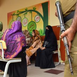 Un policía monta guardia mientras las votantes esperan para emitir su voto en un colegio electoral durante la segunda fase de las elecciones a la asamblea legislativa local en Muzaffarabad, Cachemira administrada por Pakistán, en medio de disturbios en algunas zonas de la región. | Foto:SAJJAD QAYYUM / AFP