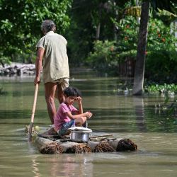 Una niña y su abuelo viajan en balsa a través de las aguas desbordadas tras las fuertes lluvias monzónicas en una aldea del distrito de Sivasagar, en Assam, India. | Foto:BIJU BORO / AFP