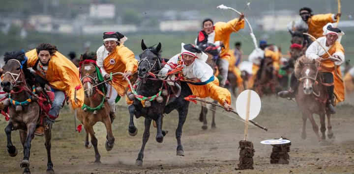 Imagen pastores realizando acrobacias ecuestres durante un evento de exhibición ecuestre con habilidades tradicionales de equitación, en el distrito de Litang, en la provincia de Sichuan, en el suroeste de China.