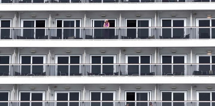 Un pasajero de crucero observa desde el balcón de un camarote a bordo de un barco de MSC Cruceros atracado en el Grand Port Maritime de Marseille, en Marsella, sureste de Francia.