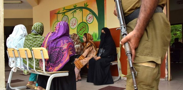 Un policía monta guardia mientras las votantes esperan para emitir su voto en un colegio electoral durante la segunda fase de las elecciones a la asamblea legislativa local en Muzaffarabad, Cachemira administrada por Pakistán, en medio de disturbios en algunas zonas de la región.
