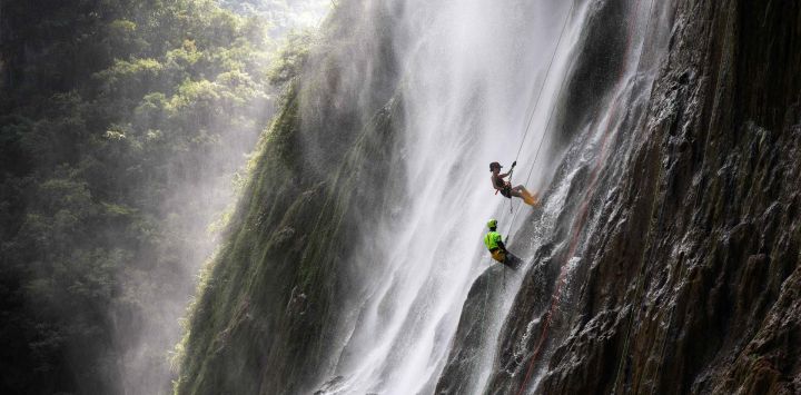 Un turista experimenta el rápel en cascada bajo la guía de un empleado en un área escénica, en la prefectura autónoma miao y dong de Qiandongnan, en la provincia de Guizhou, en el suroeste de China. El rápel en cascada en este lugar ha atraído a turistas por su refrescante alivio y la emocionante experiencia que ofrece.