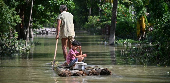 Una niña y su abuelo viajan en balsa a través de las aguas desbordadas tras las fuertes lluvias monzónicas en una aldea del distrito de Sivasagar, en Assam, India.
