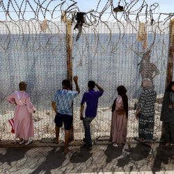 Familiares y amigos esperan junto a una valla coronada con alambre de espino el regreso de personas que habían cruzado previamente al enclave español de Ceuta, en el paso fronterizo marroquí de Bab Sebta, en las afueras de Fnideq. Hasta 60.000 migrantes entraron en Ceuta en los últimos días, la mayoría nadando alrededor del pequeño puesto fronterizo que se adentra en el mar Mediterráneo, en una oleada sin precedentes que provocó una crisis internacional para España. El cruce masivo al pequeño territorio español dejó al menos 67 muertos, según las autoridades españolas, y provocó enfrentamientos con la policía marroquí en la frontera compartida. | Foto:Abdel Majid Bziouat / AFP
