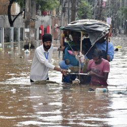 Residentes caminan por una calle inundada tras las fuertes lluvias monzónicas en Guwahati, India. | Foto:BIJU BORO / AFP