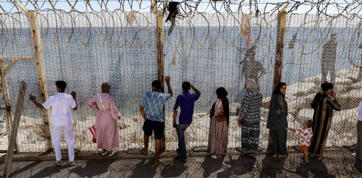 Familiares y amigos esperan junto a una valla coronada con alambre de espino el regreso de personas que habían cruzado previamente al enclave español de Ceuta, en el paso fronterizo marroquí de Bab Sebta, en las afueras de Fnideq. Hasta 60.000 migrantes entraron en Ceuta en los últimos días, la mayoría nadando alrededor del pequeño puesto fronterizo que se adentra en el mar Mediterráneo, en una oleada sin precedentes que provocó una crisis internacional para España. El cruce masivo al pequeño territorio español dejó al menos 67 muertos, según las autoridades españolas, y provocó enfrentamientos con la policía marroquí en la frontera compartida.