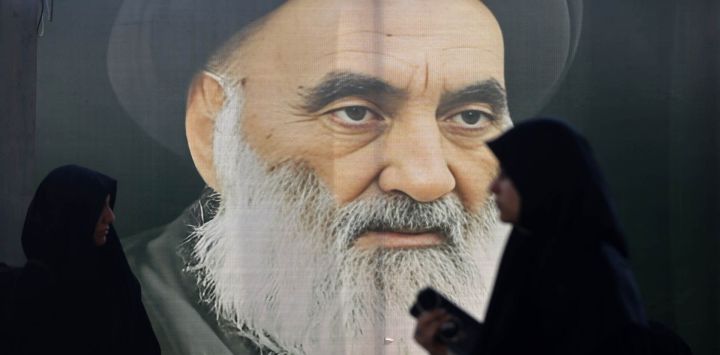 Peregrinos iraníes pasan junto a un retrato gigante del ayatolá Ali al-Sistani, la máxima autoridad religiosa chiíta, mientras se dirigen a participar en la peregrinación de Arbaeen tras cruzar la frontera entre Irak e Irán en Zurbatiyah, al sur de Bagdad.