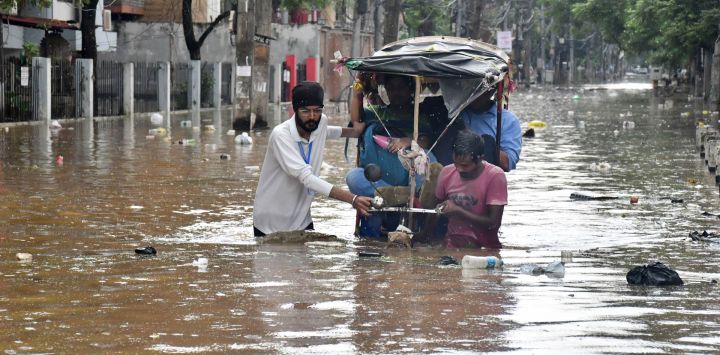 Residentes caminan por una calle inundada tras las fuertes lluvias monzónicas en Guwahati, India.