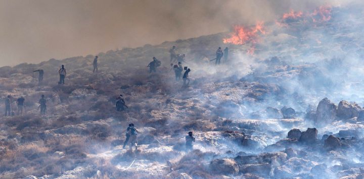 Colonos israelíes intentan extinguir un incendio forestal cerca del manantial de Ein Samiya, en la Cisjordania ocupada por Israel.