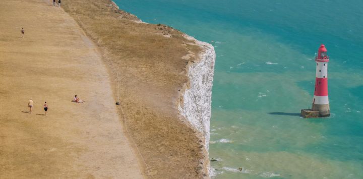 Esta vista aérea muestra a personas caminando a lo largo del acantilado sobre el faro de Beachy Head, cerca de Eastbourne, en la costa sur de Inglaterra.