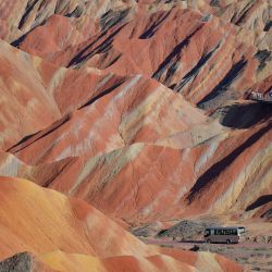 Imagen de un vehículo circulando por un camino en el área escénica de Zhangye Danxia, famosa por su relieve de Danxia caracterizado por llamativas formaciones de arenisca roja, en Zhangye, en la provincia de Gansu, en el noroeste de China. El área escénica en Gansu entró en su temporada alta de turismo en agosto, registrando una media diaria de visitantes superior a los 25.000. | Foto:Xinhua/Liu Keying