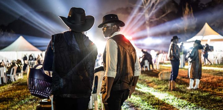Durante las celebraciones del Día Internacional del Vaquero, en el hipódromo de Ngong en Nairobi, asistentes vestidos de vaquero observan desde la distancia una actuación de música country en directo. Celebrado anualmente el Día Internacional del Vaquero conmemora la historia, la cultura y el legado perdurable de los vaqueros y vaqueras de todo el mundo. Si bien tiene sus raíces en las tradiciones de Norteamérica, la cultura vaquera y la música country han ganado cada vez más adeptos en algunas partes de África en los últimos años, especialmente en Kenia, donde la moda del Oeste, el baile en línea, la equitación y los eventos de música country han atraído a una creciente comunidad de aficionados.