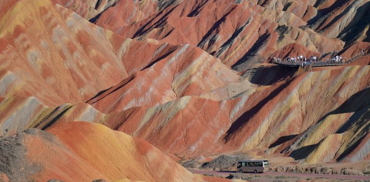 Imagen de un vehículo circulando por un camino en el área escénica de Zhangye Danxia, famosa por su relieve de Danxia caracterizado por llamativas formaciones de arenisca roja, en Zhangye, en la provincia de Gansu, en el noroeste de China. El área escénica en Gansu entró en su temporada alta de turismo en agosto, registrando una media diaria de visitantes superior a los 25.000.