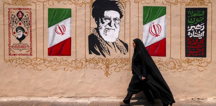 Una mujer pasa junto a un mural que representa al difunto líder supremo de Irán, Ali Khamenei, en la plaza Valiasr, en el centro de Teherán. Las esperanzas de un inminente acuerdo entre Estados Unidos e Irán para poner fin al bloqueo del estrecho de Ormuz aumentaron el optimismo de que el petróleo y el gas, junto con otros productos clave, volverían a fluir libremente después de más de cinco meses de guerra. Pero los precios del petróleo subieron antes del fin de semana ante la ausencia de confirmación de un acuerdo, en medio de informes de que Irán planeaba bloquear el paso de barcos estadounidenses e israelíes por la vía marítima.
