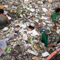 Trabajadores recogen basura arrastrada por la corriente de un río durante las intensas lluvias provocadas por el monzón del suroeste días antes, cerca de un centro comercial en la ciudad de Paranaque, en las afueras de Manila, Filipinas. | Foto:TED ALJIBE / AFP