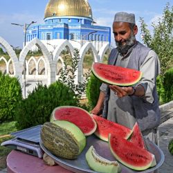 Un vendedor afgano corta sandías mientras espera clientes en la cima de la colina Wazir Akbar Khan en Kabul. | Foto:WAKIL KOHSAR / AFP