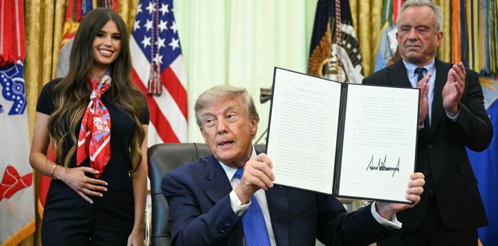 El presidente estadounidense Donald Trump firma una orden ejecutiva que exige mayor investigación y flexibilidad en materia de vacunas, junto al secretario de Salud y Servicios Humanos, Robert F. Kennedy Jr. (derecha), y Jayme Leagh Franklin (izquierda), fundadora de The Conservateur, en el Despacho Oval de la Casa Blanca en Washington, D.C..