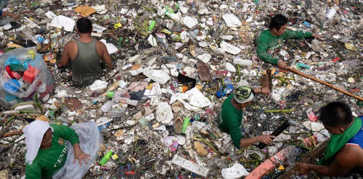 Trabajadores recogen basura arrastrada por la corriente de un río durante las intensas lluvias provocadas por el monzón del suroeste días antes, cerca de un centro comercial en la ciudad de Paranaque, en las afueras de Manila, Filipinas.