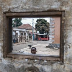 Un niño mira por una ventana en una pared del pueblo de Pantufo, cerca de Santo Tomé, capital de Santo Tomé y Príncipe. Pantufo es un pintoresco pueblo pesquero situado en la costa de la isla de Santo Tomé, al sureste de la capital, en el distrito de Agua Grande. La localidad es famosa por su playa, su auténtico ambiente costero y sus fiestas tradicionales. | Foto:DANIEL BELOUMOU OLOMO / AFP