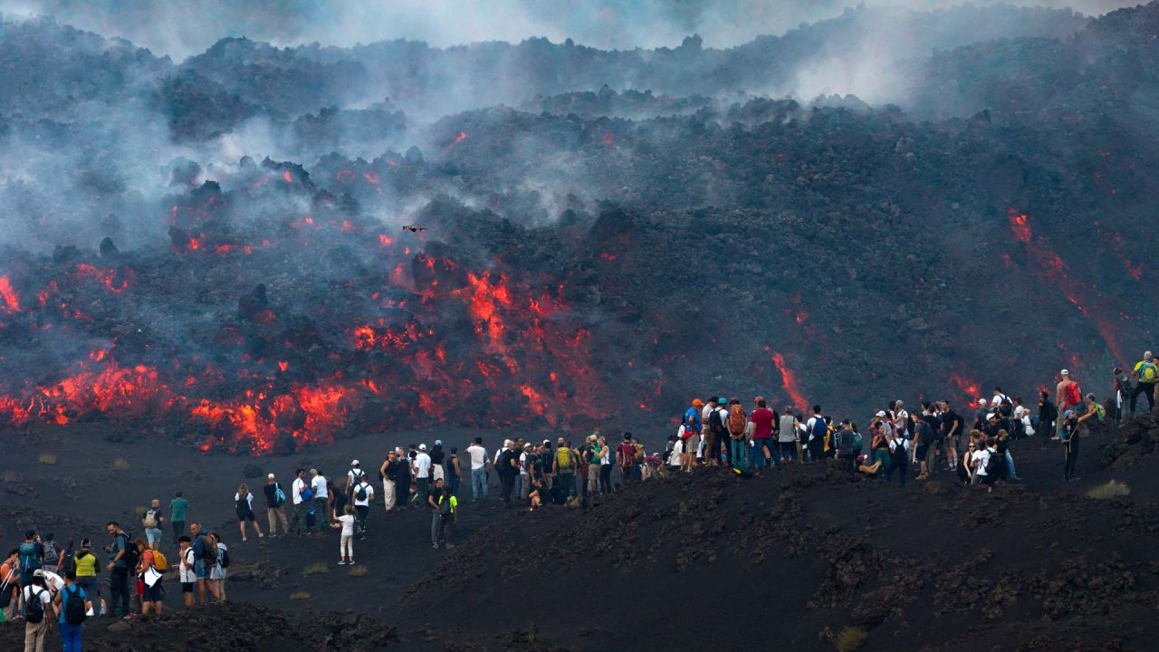 Esta fotografía, distribuida por Etna Walk, muestra a visitantes junto a la lava que fluye del volcán Etna durante una erupción en Catania, en la isla mediterránea de Sicilia, Italia. | Foto:Etna Walk / AFP