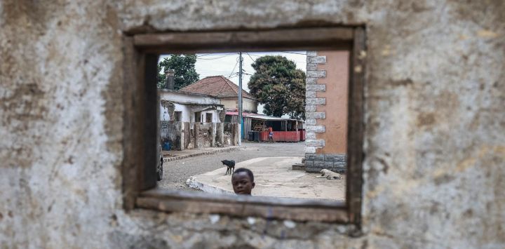 Un niño mira por una ventana en una pared del pueblo de Pantufo, cerca de Santo Tomé, capital de Santo Tomé y Príncipe. Pantufo es un pintoresco pueblo pesquero situado en la costa de la isla de Santo Tomé, al sureste de la capital, en el distrito de Agua Grande. La localidad es famosa por su playa, su auténtico ambiente costero y sus fiestas tradicionales.