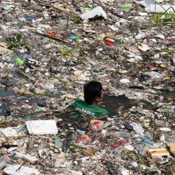 Un trabajador nada entre la basura arrastrada por un río durante las intensas lluvias provocadas por el monzón del suroeste días antes, cerca de un centro comercial en la ciudad de Parañaque, en las afueras de Manila, Filipinas. Inundaciones, desmalezamientos de tierra y accidentes causados por un aguacero de nueve días equivalente a más de un mes de lluvia en algunas zonas han dejado al menos 16 muertos en el norte de Filipinas, según informaron los rescatistas. | Foto:TED ALJIBE / AFP