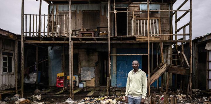 Francis Tugbiyele, de 42 años, representante de la comunidad, posa para una fotografía frente a la casa de su tío, que está siendo dañada por la erosión costera, en Ayetoro, estado de Ondo. Francis se aloja con su tío después de que su propia casa fuera destruida por la erosión costera y ahora se enfrenta a la reubicación por cuarta vez. "Estoy desesperado y asustado porque puede ocurrir en cualquier momento", dijo, refiriéndose a la posibilidad de que la casa de su tío sea destruida. La comunidad costera de Ayetoro, en el estado de Ondo, al suroeste de Nigeria, se ha convertido en uno de los ejemplos más visibles del país sobre la vulnerabilidad de las comunidades que viven a lo largo del océano Atlántico ante la erosión costera y el aumento del nivel del mar.