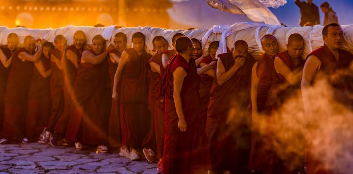 Monjes transportan una enorme pintura thangka enrollada de Buda en el Monasterio de Drepung, en Lhasa, en la región autónoma de Xizang, en el suroeste de China.
