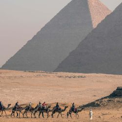Turistas montan camellos en el punto escénico de las Pirámides, en Giza, Egipto. | Foto:Xinhua/Ahmed Gomaa