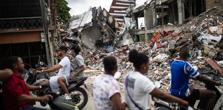 Personas en motocicletas pasan frente a un edificio destruido en el barrio Medrano de Quibdó, departamento del Chocó, Colombia, días después del terremoto de magnitud 7.4. Al menos 287 personas han muerto, miles han resultado heridas y unas 379 permanecen desaparecidas, ya que las probabilidades de encontrar sobrevivientes han disminuido drásticamente desde que transcurrieron las cruciales 72 horas, aunque voluntarios y equipos de rescate continúan excavando entre los escombros en busca de cualquier señal de vida.