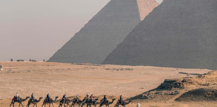 Turistas montan camellos en el punto escénico de las Pirámides, en Giza, Egipto.