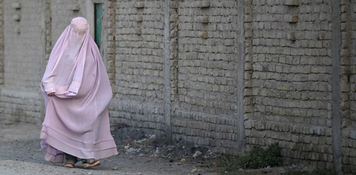 Una mujer afgana vestida con burka camina por una calle del distrito de Dand, en Kandahar, Afganistán.