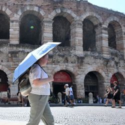 Una turista se cubre del sol con una sombrilla cerca de la Arena di Verona, en Verona, Italia. | Foto:Xinhua/Alberto Lingria