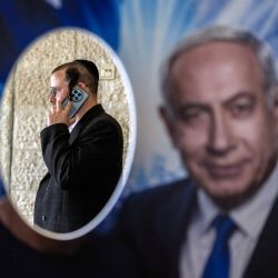 Un miembro del partido Likud aparece en una fotografía tomada frente a un cartel con la imagen del primer ministro israelí, Benjamin Netanyahu, en un colegio electoral durante las primarias del partido, previas a las elecciones nacionales del país, en Jerusalén. Israel celebrará elecciones nacionales el 27 de octubre, la última fecha permitida por la ley, según anunció su parlamento. | Foto:ilia yefimovich / AFP