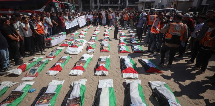 Dolientes se congregan alrededor de bolsas para cadáveres cubiertas con banderas que contienen los restos de palestinos muertos en ataques israelíes durante la guerra con Hamás y recientemente recuperados de entre los escombros, durante un funeral masivo en la ciudad de Gaza.