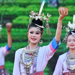 Imagen de actrices realizando una presentación durante un evento promocional, en el distrito autónomo dong de Sanjiang, en el sur de China. Un evento promocional para operadores turísticos se llevó a cabo aquí el jueves, en el que se exhibieron la cultura étnica y los recursos turísticos de la región mediante espectáculos, un tradicional "Banquete de las Cien Familias" y otras actividades. | Foto:Xinhua/Lu Boan