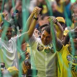 El senador brasileño Flavio Bolsonaro se da la mano con el diputado Douglas Ruas y el diputado Carlos Jordy durante un acto de su campaña presidencial en el gimnasio Maracanazinho de Río de Janeiro, Brasil. | Foto:MAURO PIMENTEL / AFP
