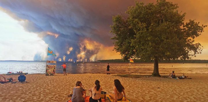 Bañistas se sientan en la playa de Moutchic, en Lacanau, al suroeste de Francia, mientras columnas de humo se elevan hacia el cielo a causa de un incendio forestal. El fuego, que azota la zona norte de la cuenca de Arcachon, en la región de Gironda, al suroeste de Francia, ha arrasado más de 3.400 hectáreas, según las últimas cifras publicadas por la prefectura.