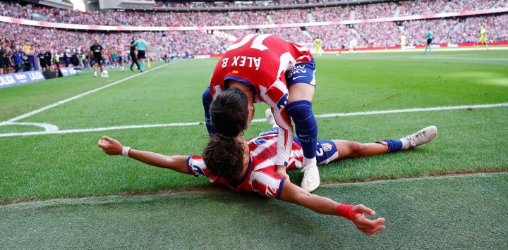 El delantero argentino del Atlético de Madrid Giuliano Simeone (abajo) celebra con el delantero español del Atlético de Madrid Alex Baena anotando el segundo gol de su equipo durante el partido de fútbol de la liga española entre el Club Atlético de Madrid y el Villarreal CF en el Estadio Metropolitano de Madrid.