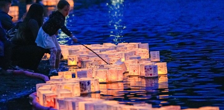 Imagen de una niña soltando una linterna iluminada en el agua durante el Festival de Linternas Acuáticas en el Parque Town Centre, en Coquitlam, Columbia Británica, Canadá. El festival invitó a los participantes a decorar linternas con mensajes de esperanza, sueños y recuerdos antes de soltarlas al agua.