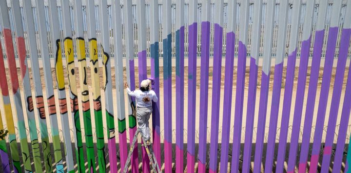 Esta vista aérea muestra a la voluntaria Joselyn Valladares pintando el muro fronterizo entre Estados Unidos y México en homenaje a las madres de personas desaparecidas, como parte de una campaña de Amnistía Internacional para crear conciencia sobre las personas desaparecidas y las familias que las buscan, en Playas de Tijuana, Baja California, México.