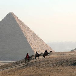 Turistas montan camellos en el punto escénico de las Pirámides, en Giza, Egipto. | Foto:Xinhua/Ahmed Gomaa